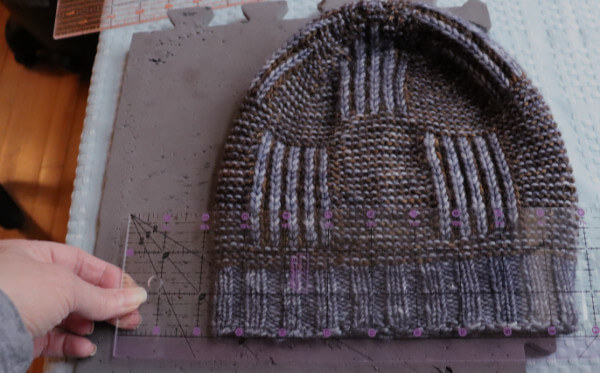 Using a transparent quilters ruler to measure and  keep the edges of a hat straight