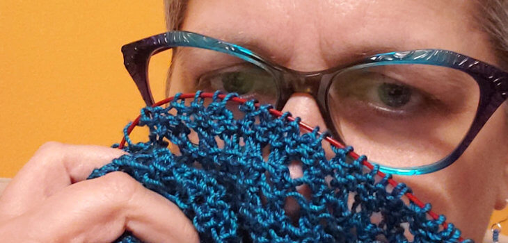 Knitting Doesn't Relieve My Stress. Close-up picture of Brenda's eyes and blue glasses, she ishiding behind her knitting.